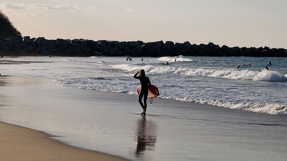 a person with a surfboard walking on the beach