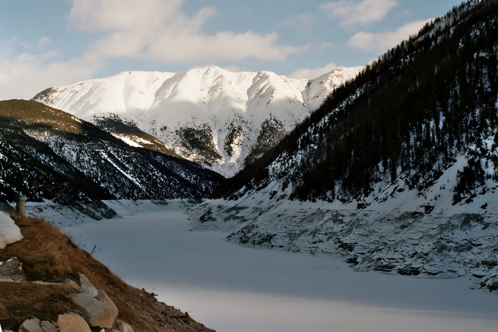 a snow covered mountain range with rocks and snow on the ground
