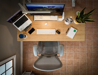 an overhead view of a desk with a laptop, keyboard, mouse, and a