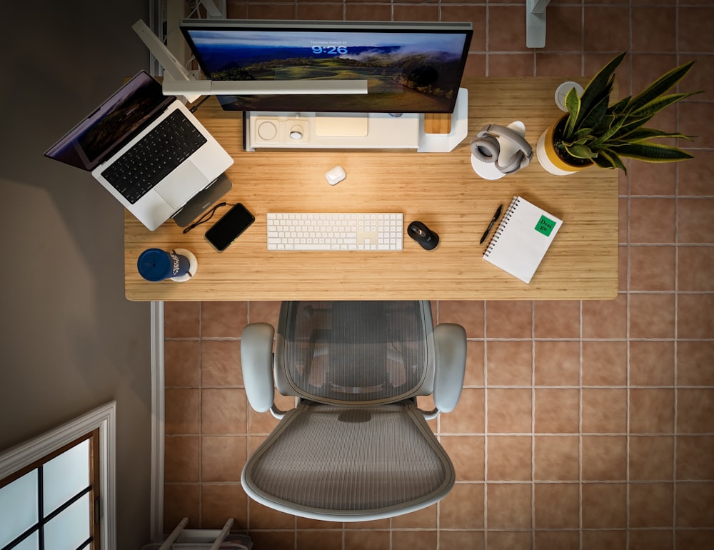 an overhead view of a desk with a laptop, keyboard, mouse, and a