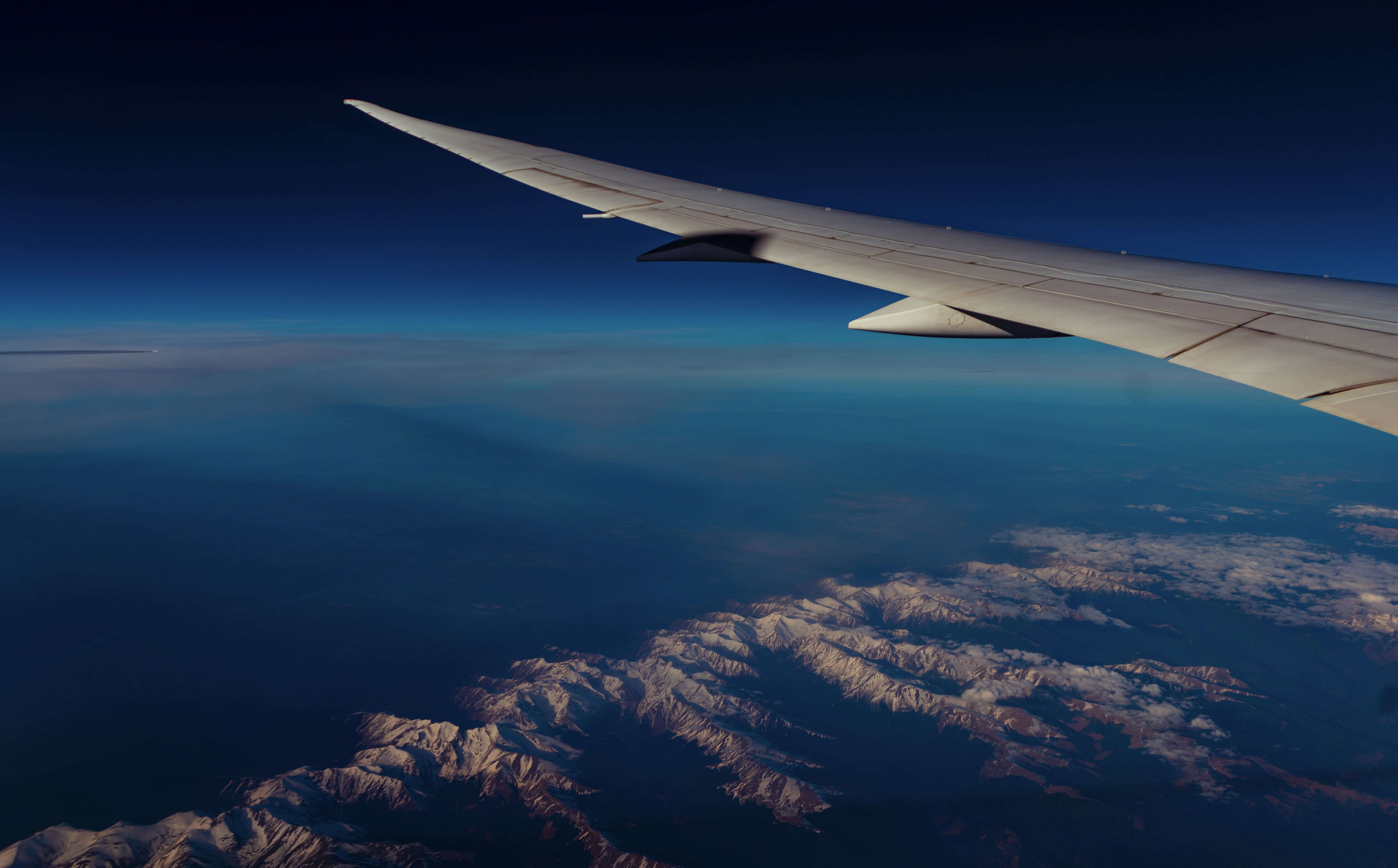 the wing of an airplane flying over a mountain range, 