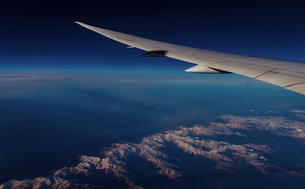 the wing of an airplane flying over a mountain range