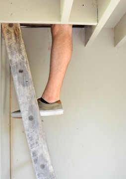 a man standing on top of a wooden ladder