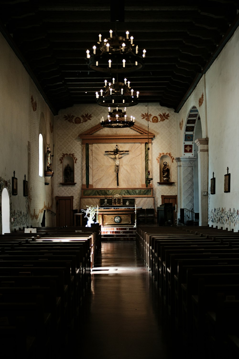 a dimly lit church with pews and a chandelier