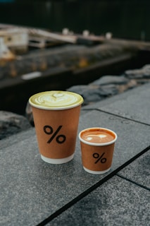 two cups of coffee sitting on a ledge