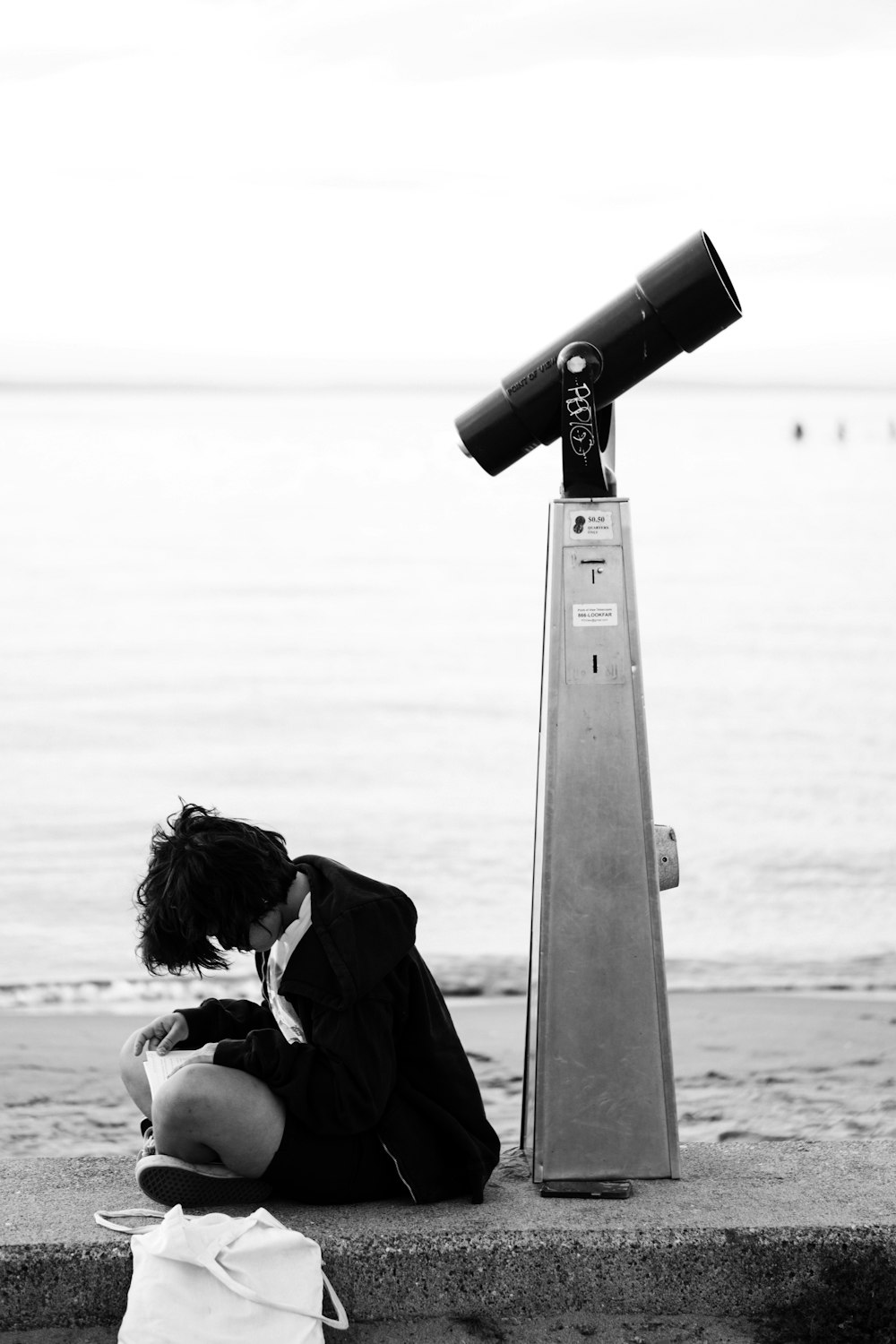 a person sitting on a ledge next to a telescope