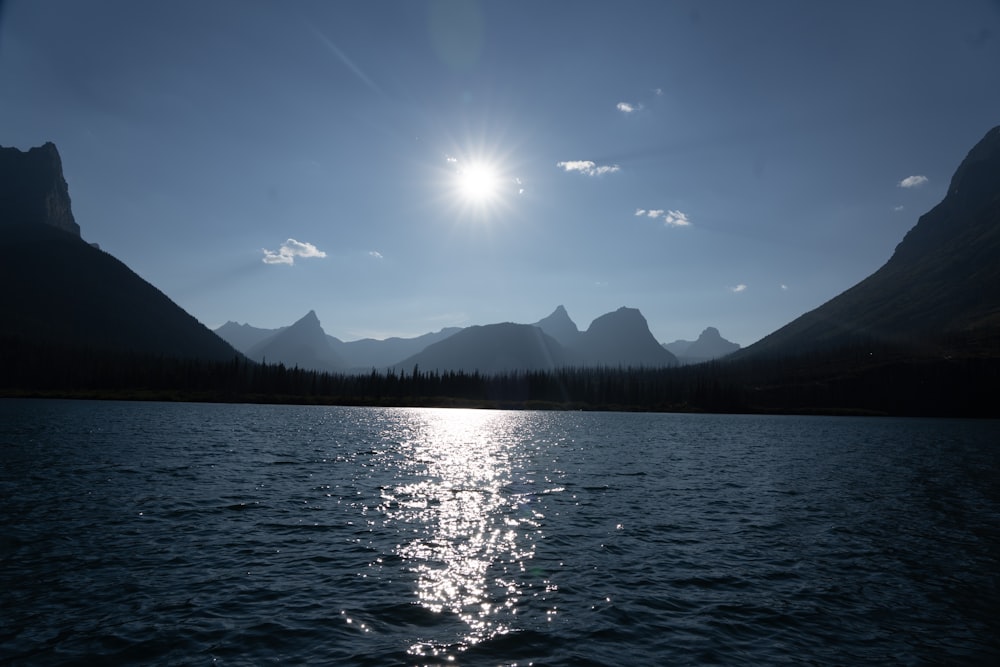 the sun shines brightly over a mountain lake