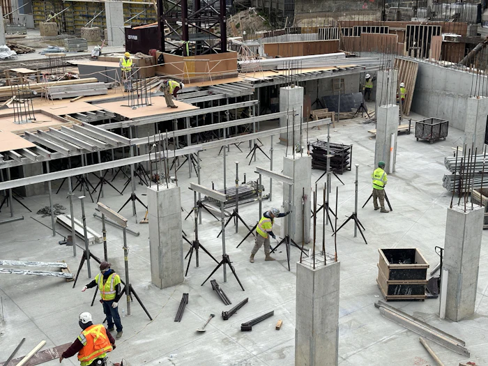 Cast-in-place concrete columns rising from a parkade floor slab while the crew sets formwork and shoring.