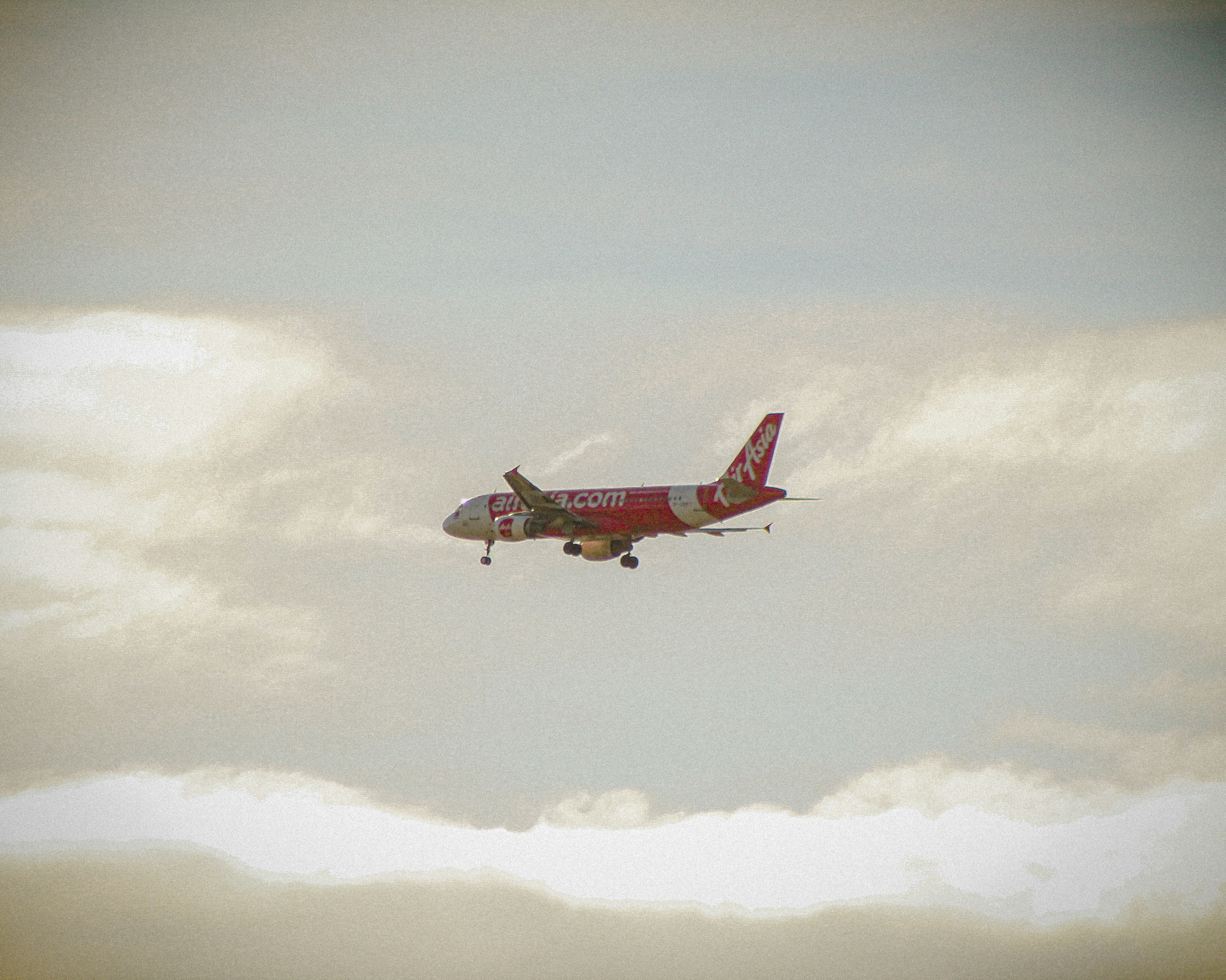 a red and white airplane flying through a cloudy sky