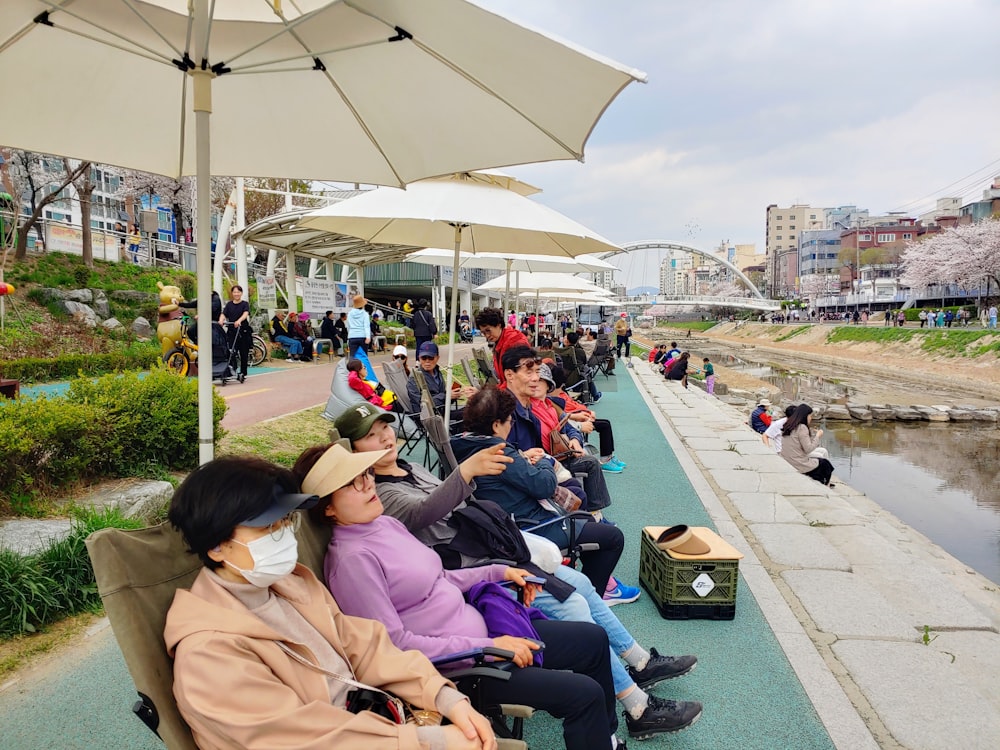 a group of people sitting next to each other under umbrellas