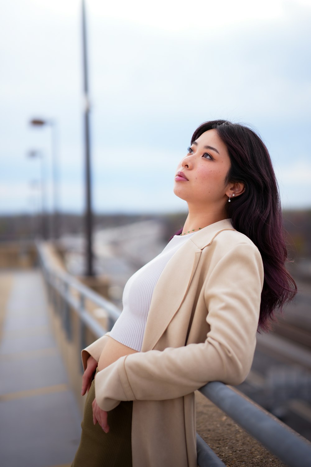 a woman leaning on a rail next to a train track