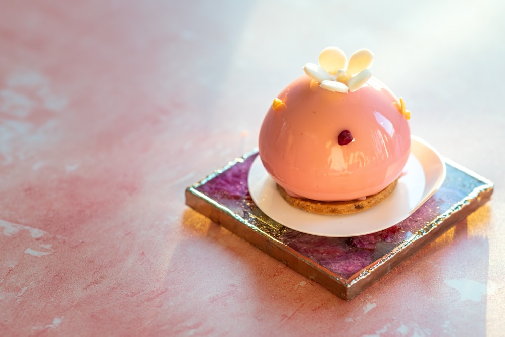 a small pink piggy bank sitting on top of a plate