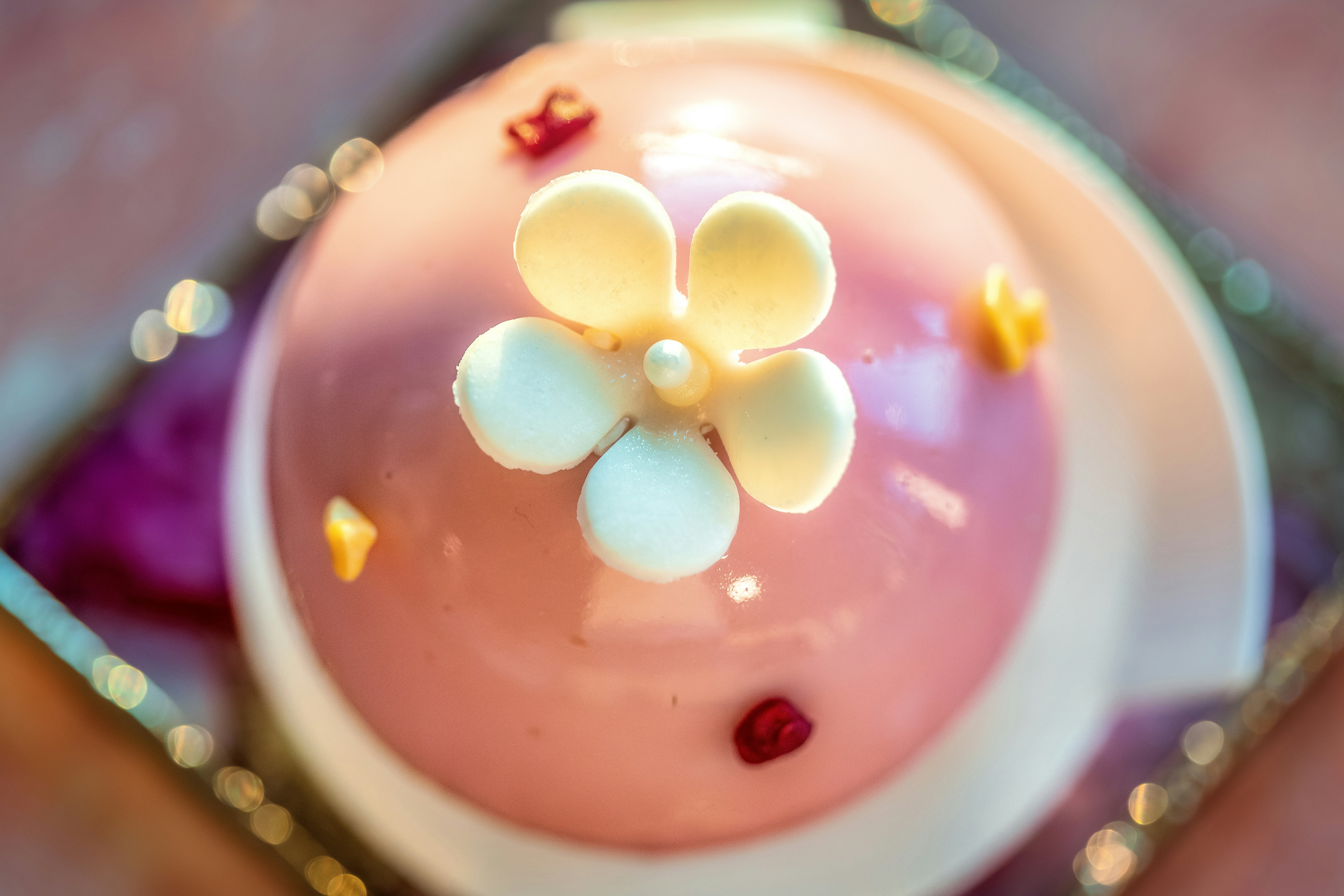 Close-up of a decorated pink cake with a white flower