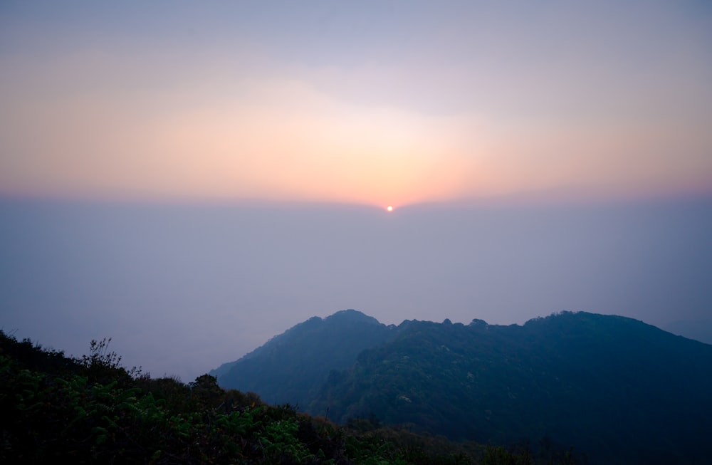 the sun is setting over a mountain range