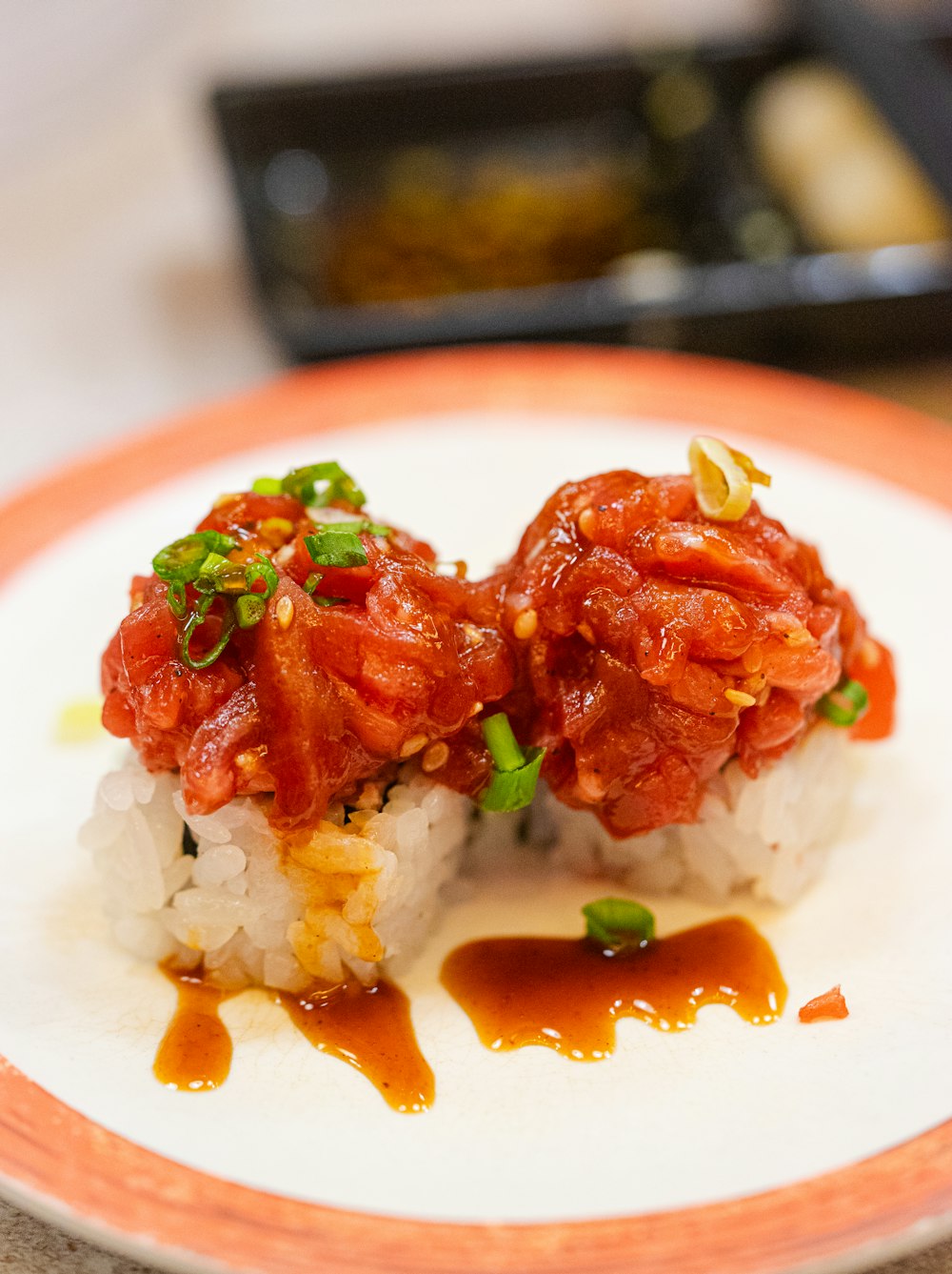 two pieces of sushi on a plate with sauce