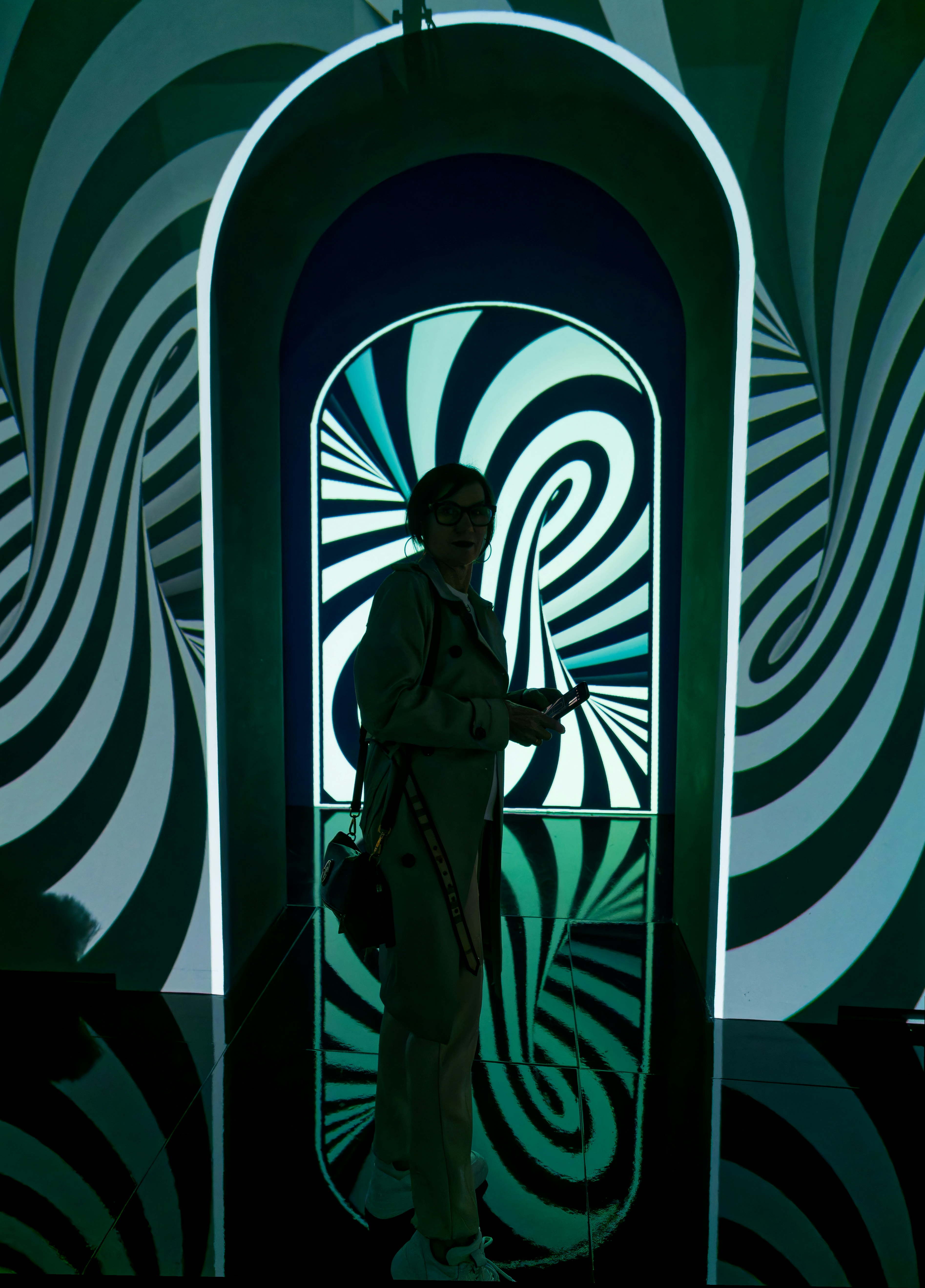 Person holding a smartphone inside a room with swirling projections.