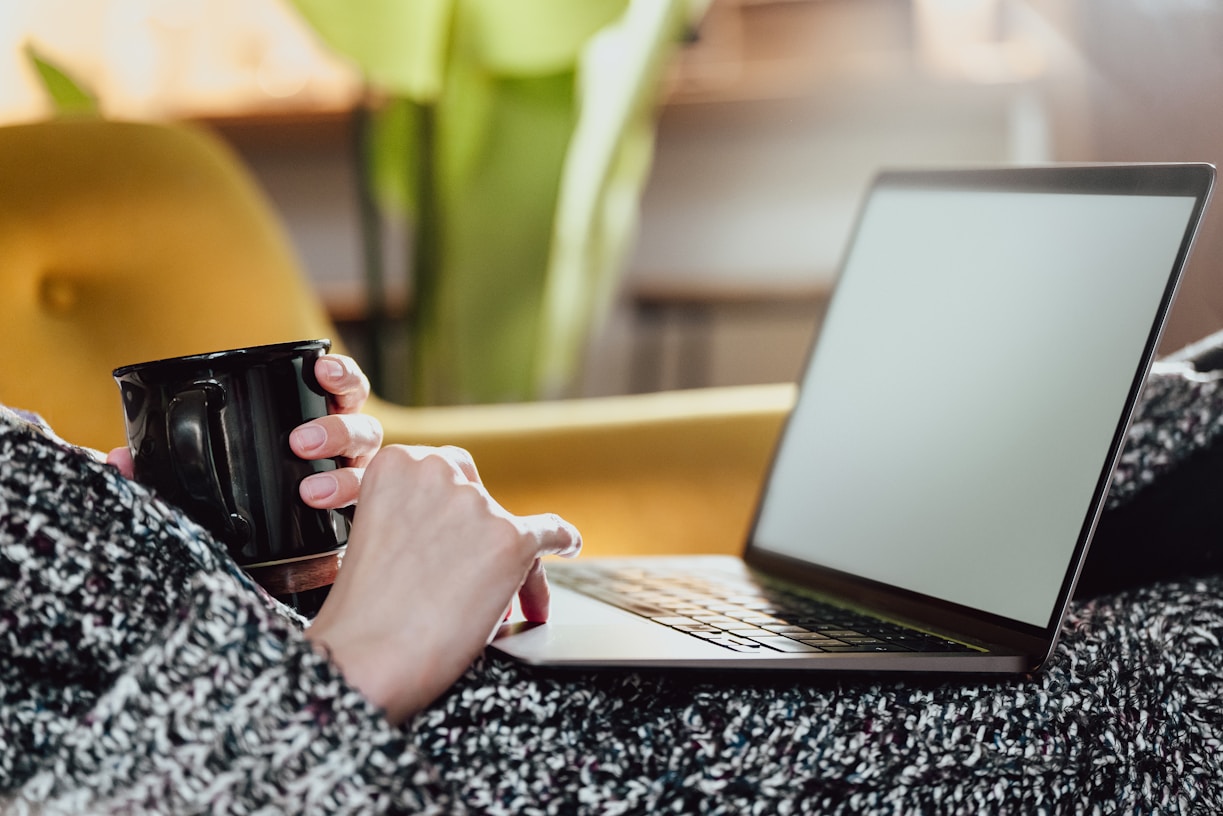 a woman holding a coffee mug while using a laptop