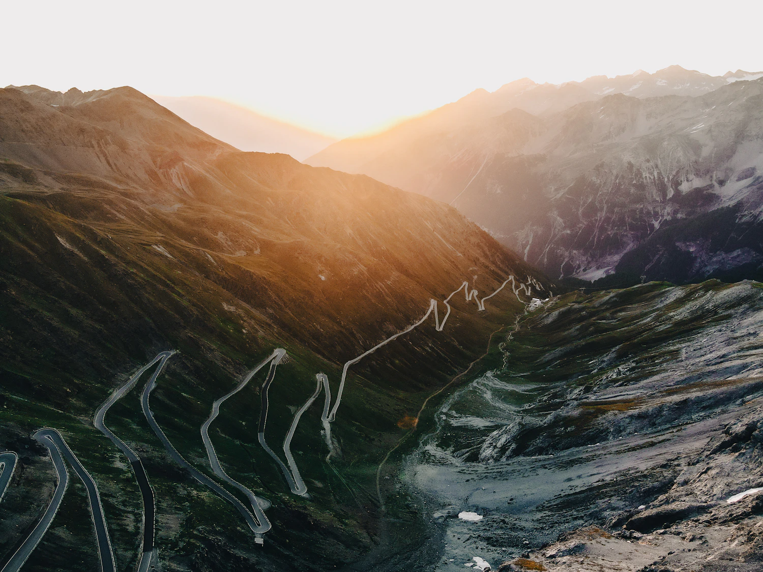 Hairpin switchbacks climbing a mountain pass at sunrise