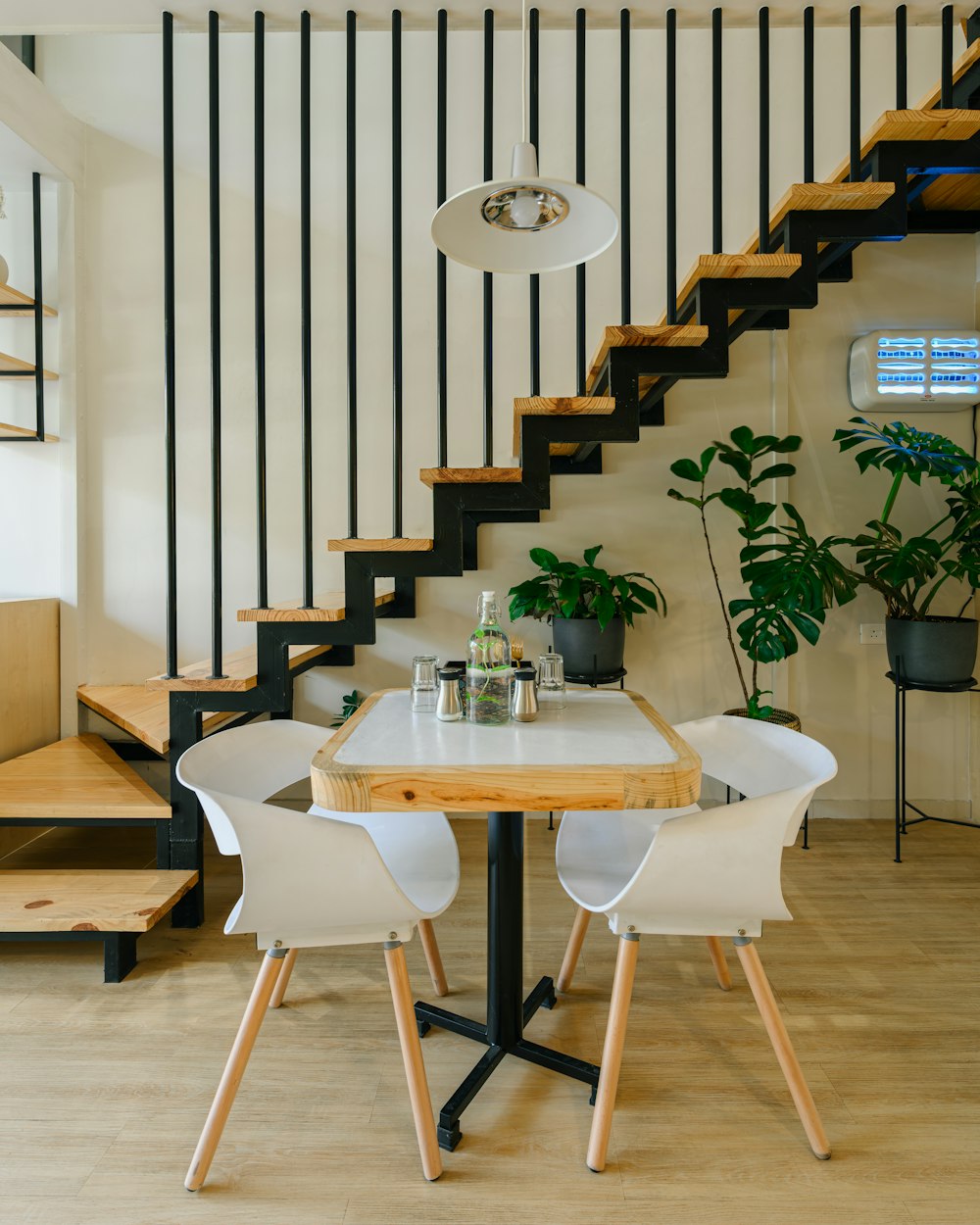 a table with two chairs under a stair case