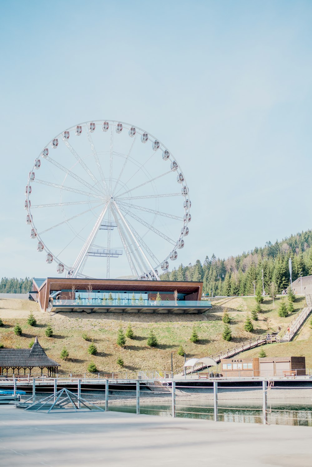 uma grande roda gigante sentada no topo de uma colina verde exuberante