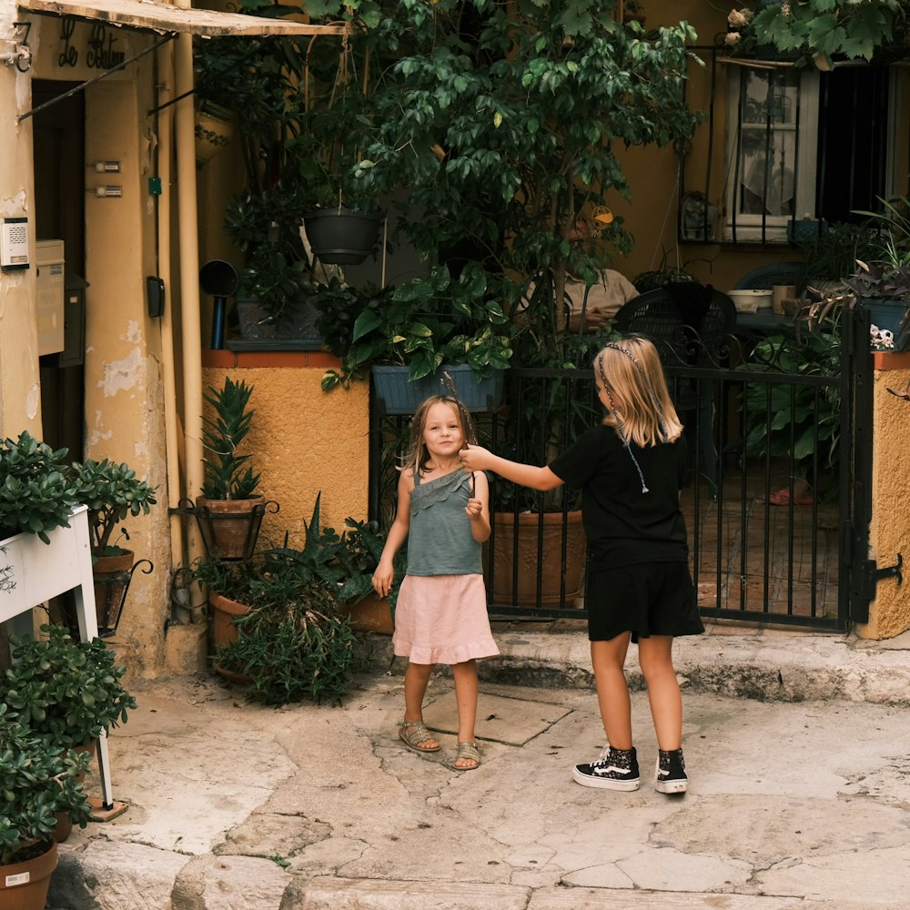 two little girls standing in front of a house