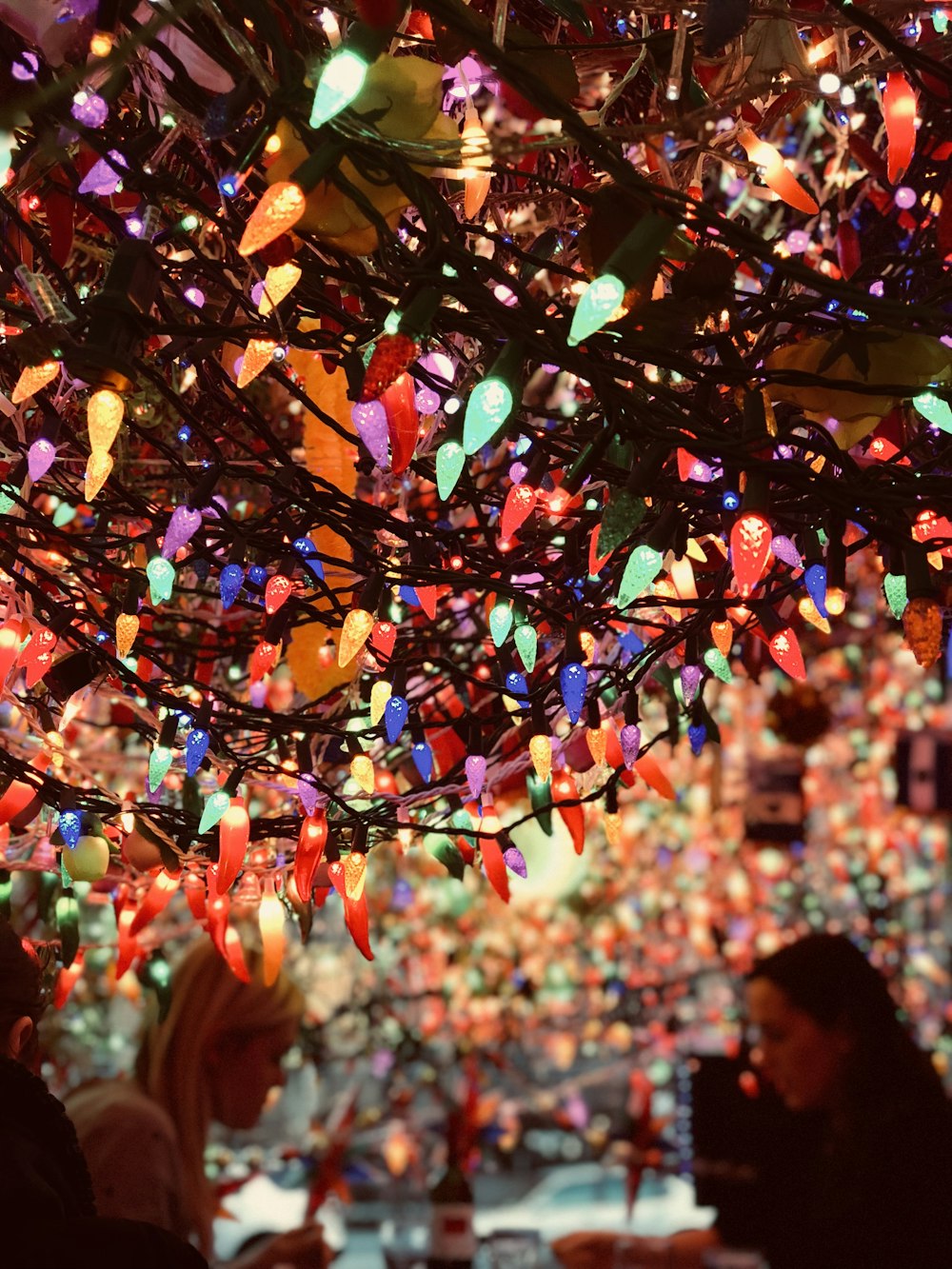 a group of people sitting at a table under a christmas tree