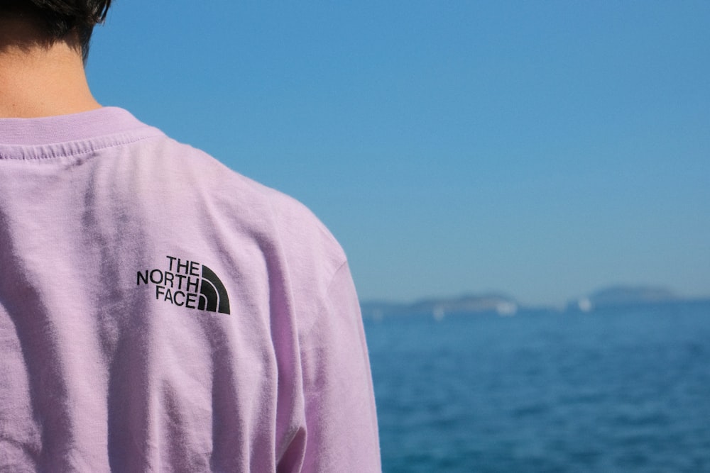 a man wearing a purple shirt looking out at the ocean