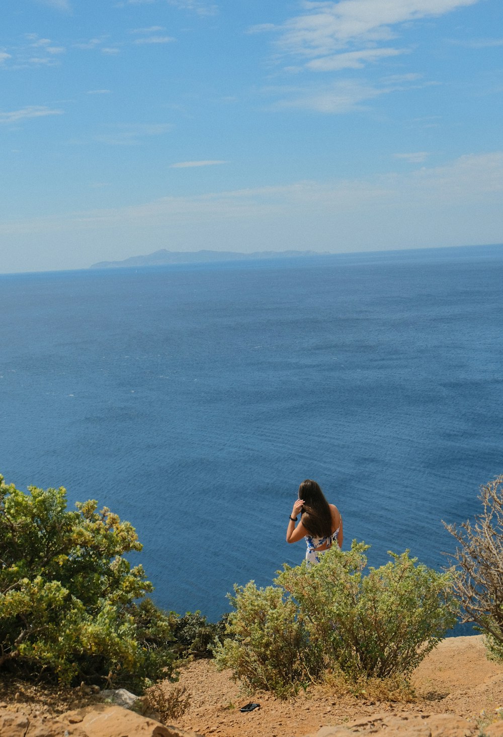 a woman standing on top of a hill next to the ocean