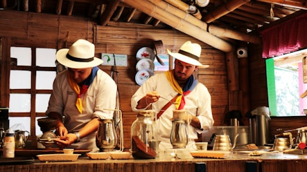 a couple of men standing in a kitchen preparing food