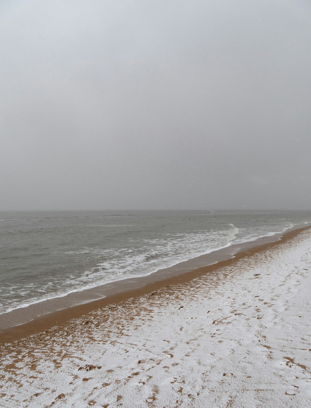 a beach covered in snow next to the ocean