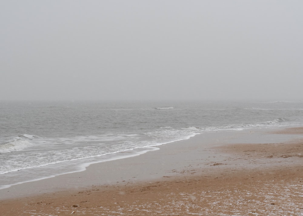 a person walking on a beach with a surfboard