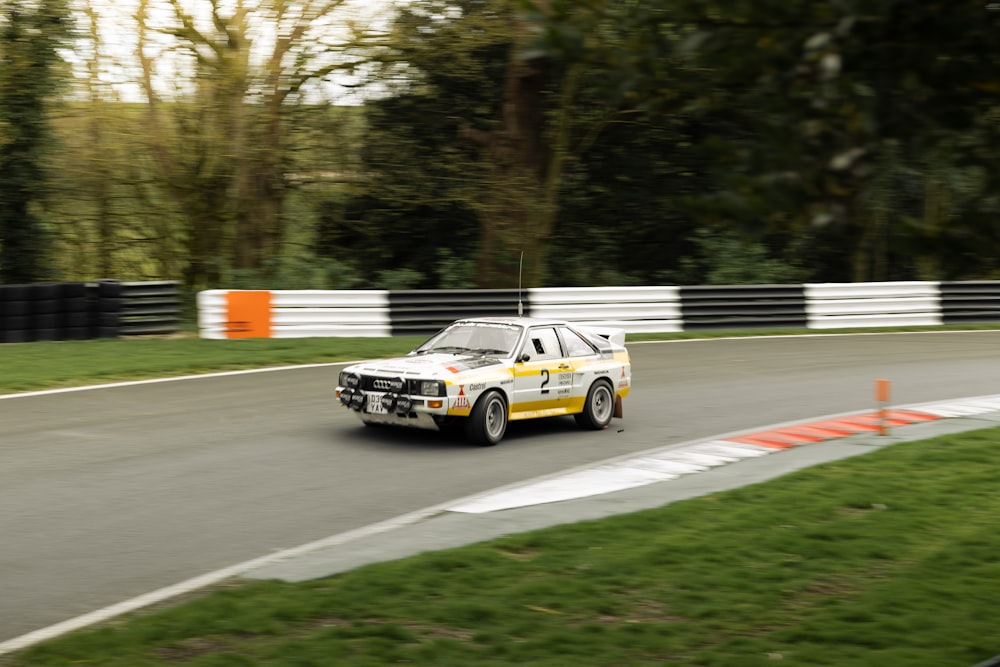 a white and yellow car driving down a race track