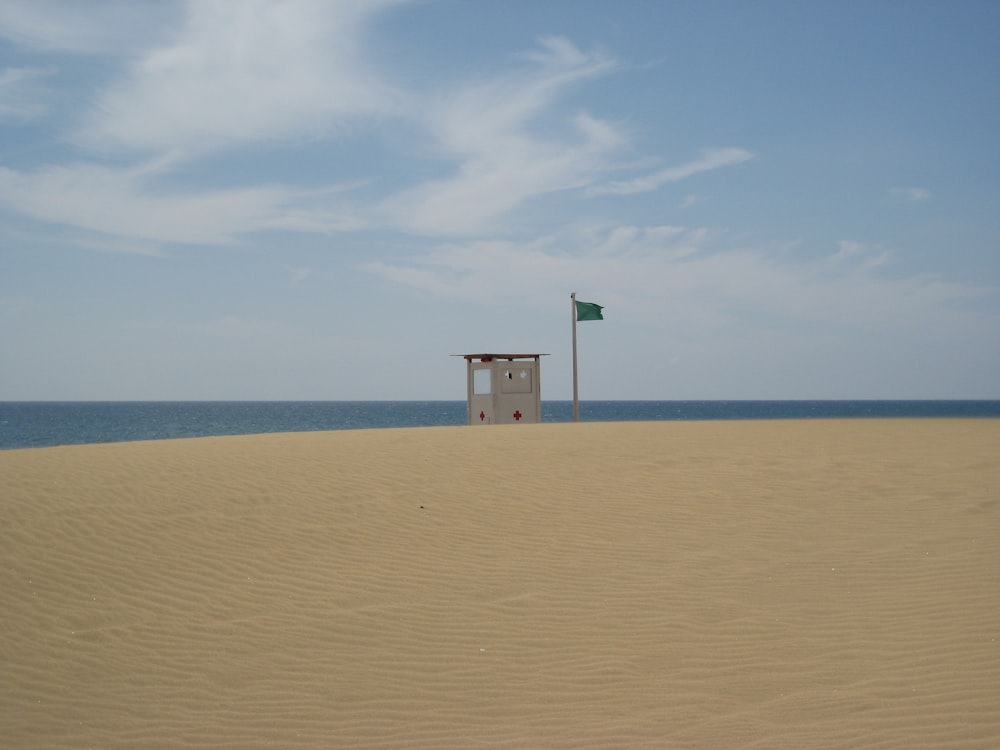 a lifeguard station on the beach with a flag flying