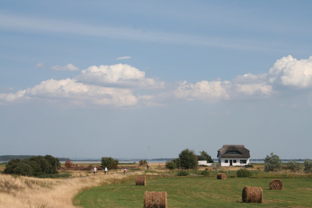 a field with hay bales in the foreground and a house in the background