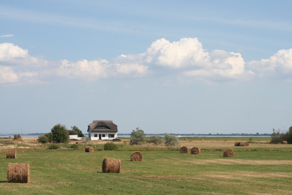 a field with hay bales and a house in the distance