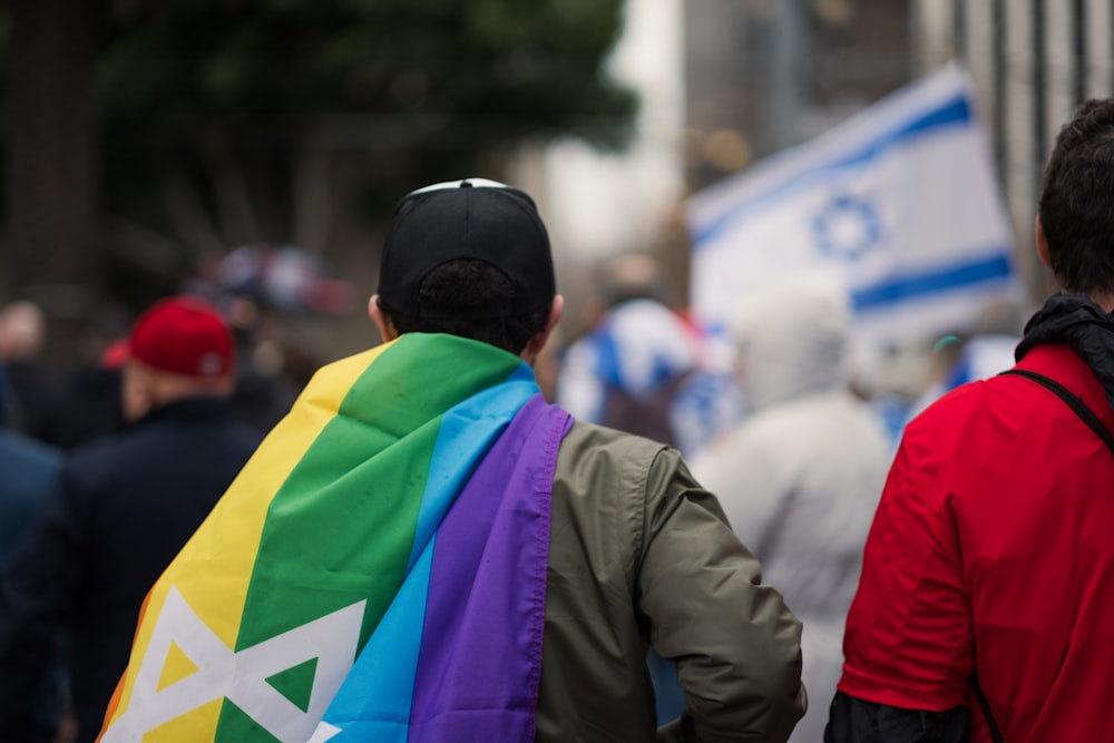a couple of men walking down a street holding a rainbow flag