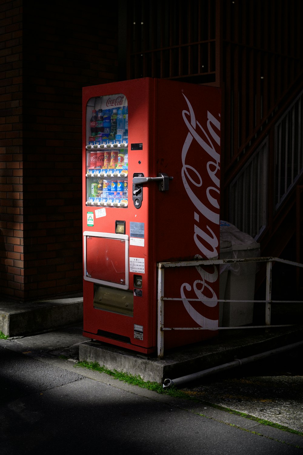 Una máquina de coca - cola sentada al costado de una calle