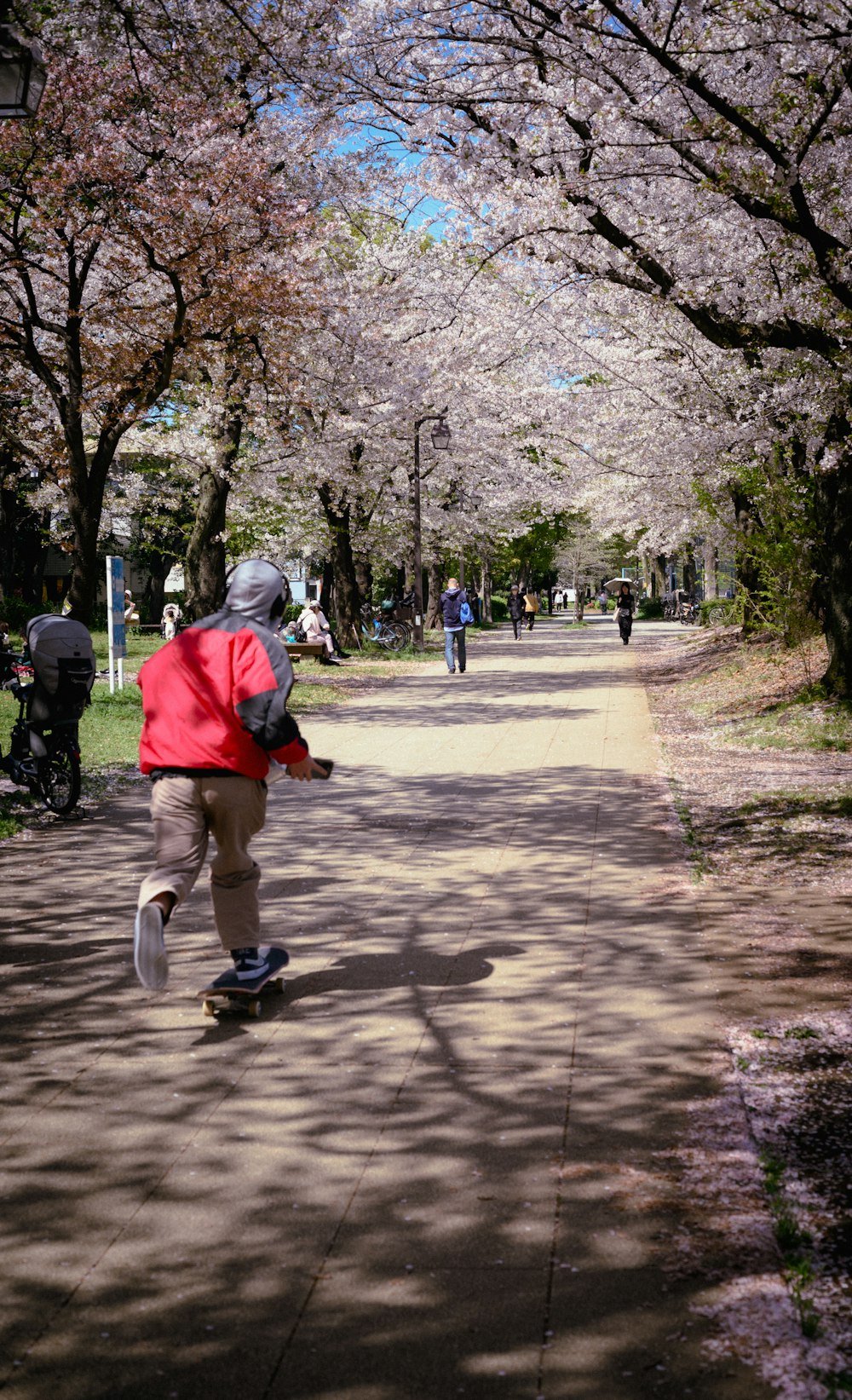 a person in a red jacket is skateboarding down a path