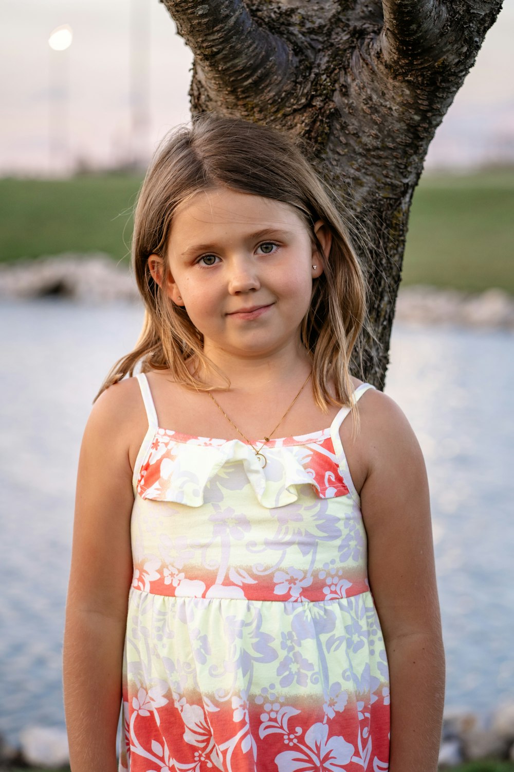 a little girl standing in front of a tree