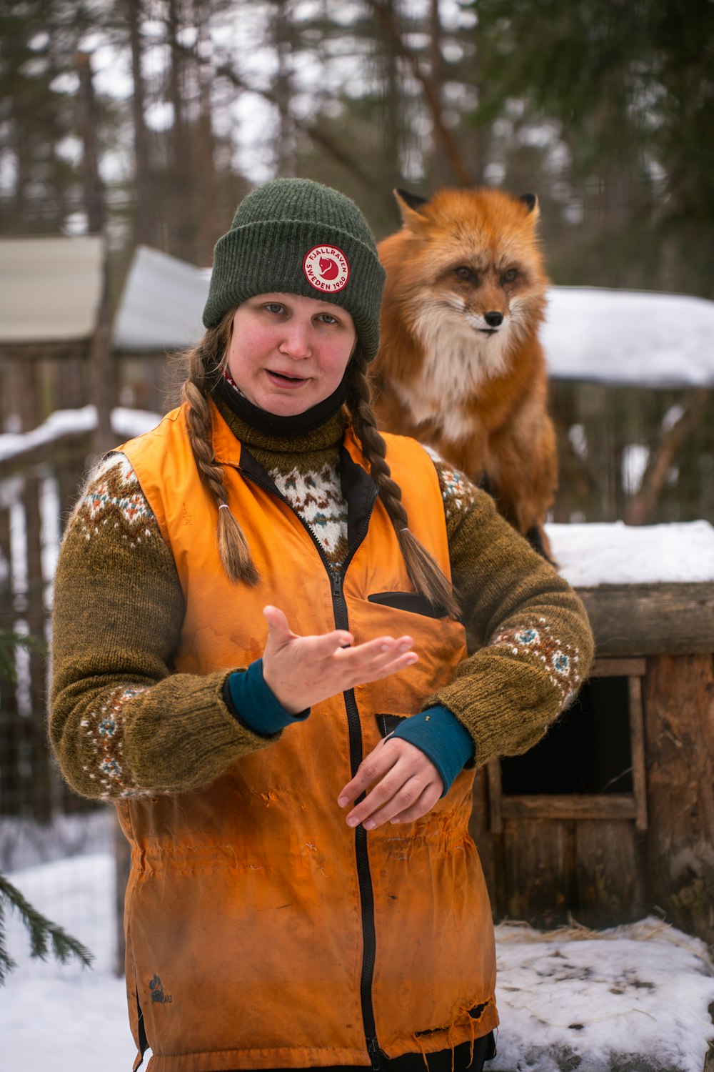 a woman standing in front of a fox in the snow