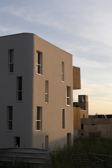 a tall white building sitting next to a lush green field
