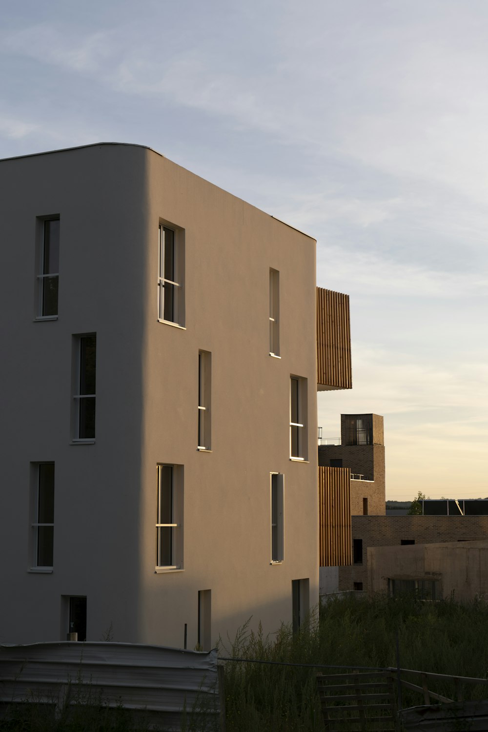 a tall white building sitting next to a lush green field