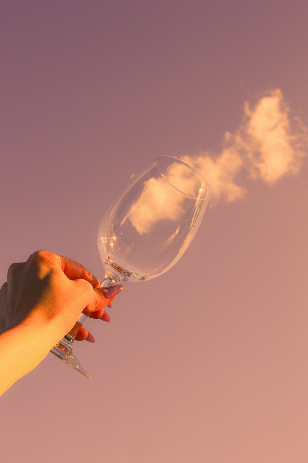 a hand holding a wine glass with smoke coming out of it