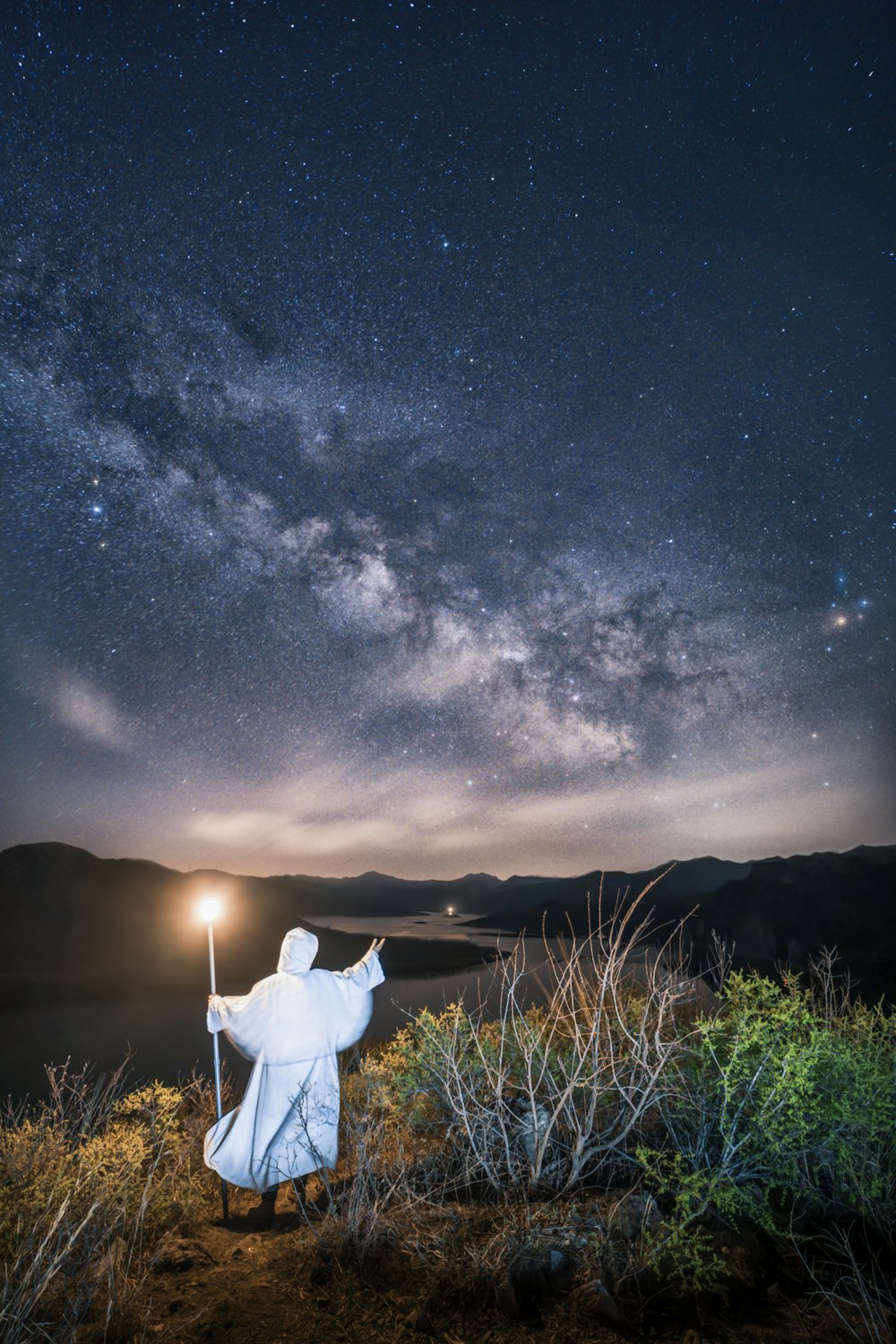 a statue of a person holding a light saber under a night sky filled with stars