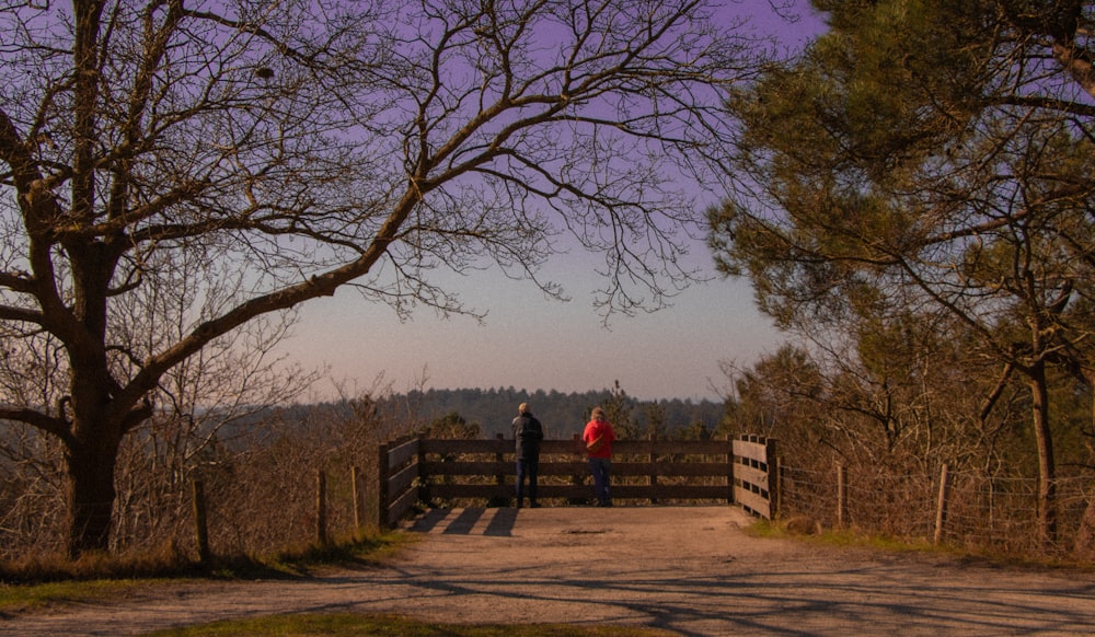 a couple of people standing on top of a dirt road