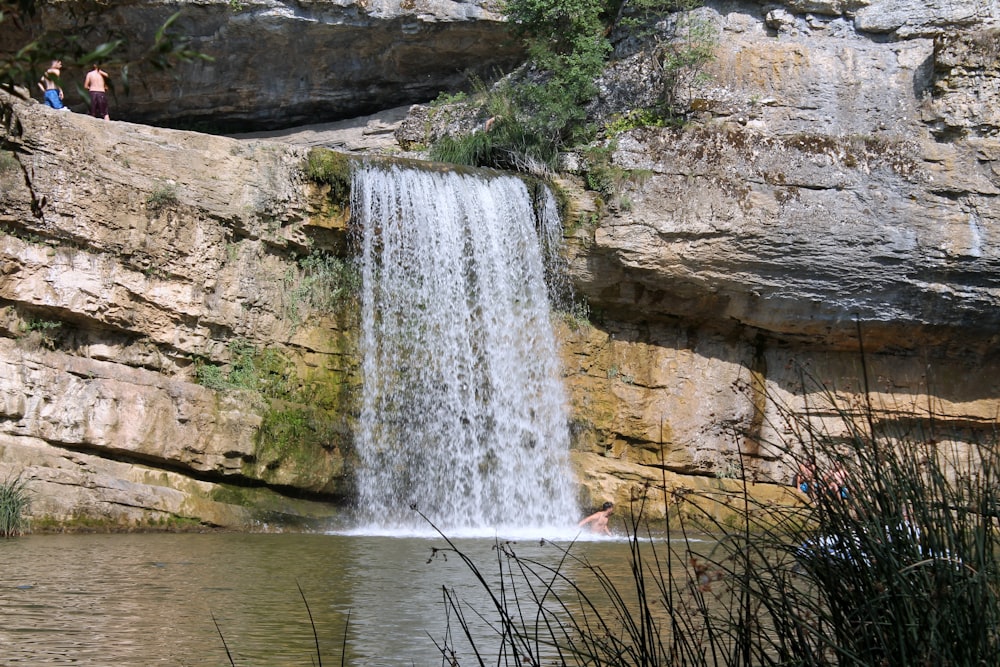 a man swimming in a pool next to a waterfall