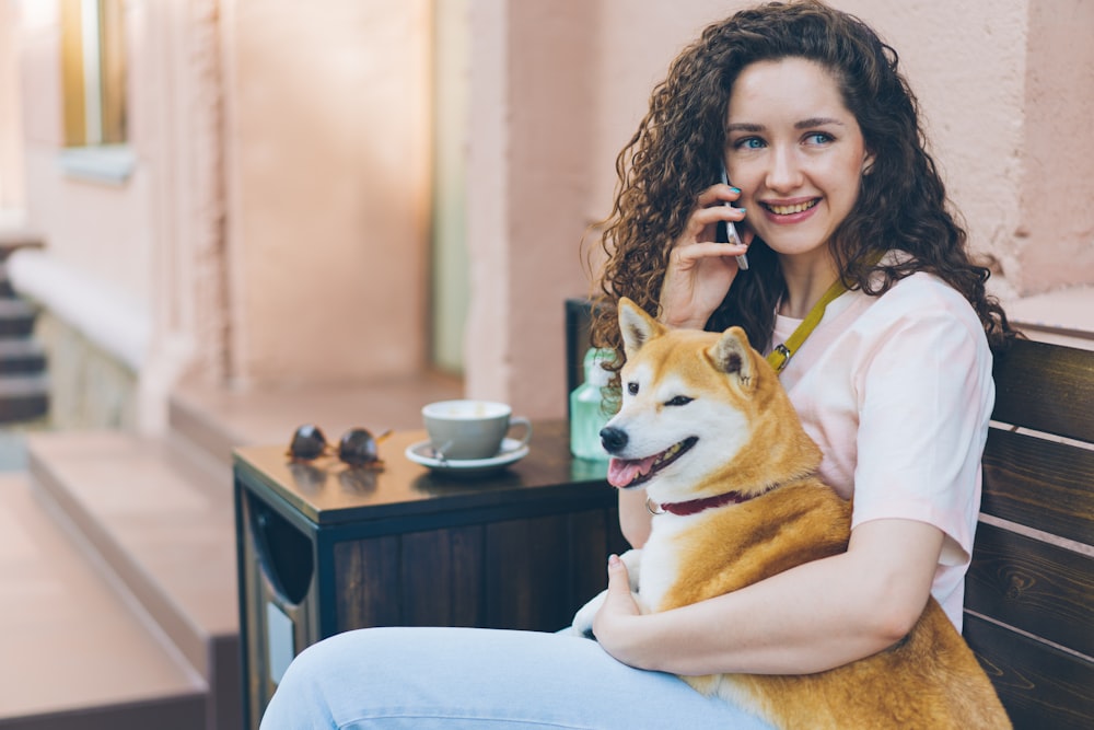 eine Frau sitzt auf einer Bank mit einem Hund auf dem Schoß