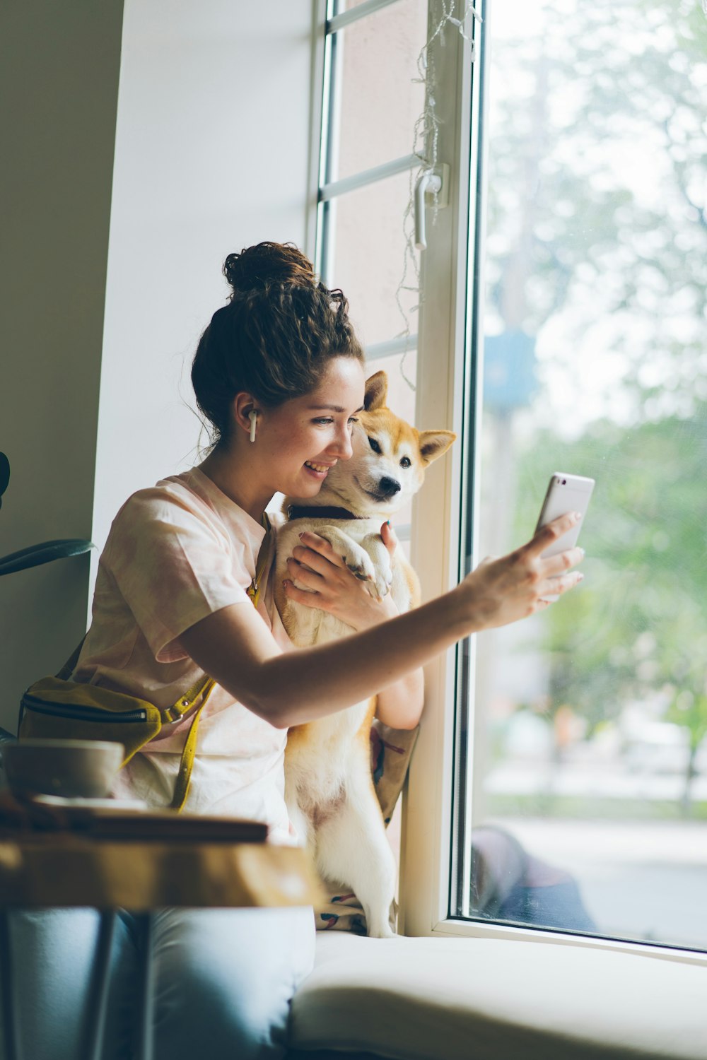 a woman holding a dog and looking at a cell phone