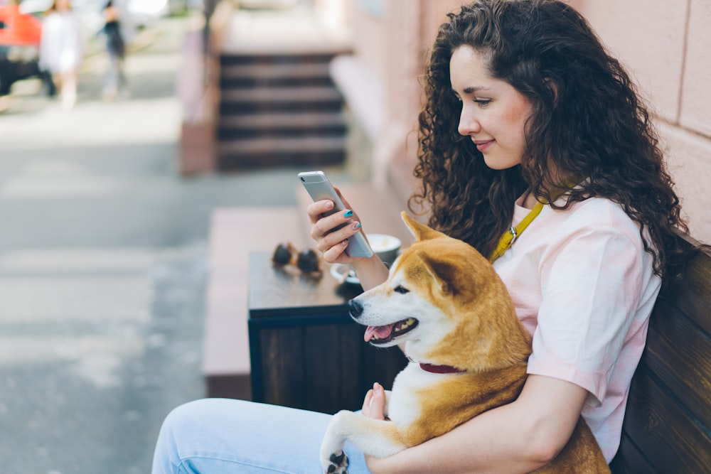 a woman sitting on a bench holding a dog