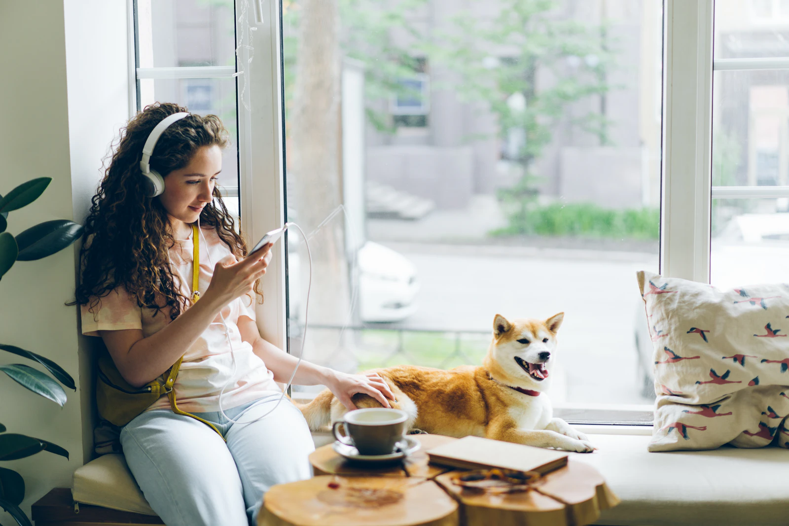 Perro tumbado junto a la mesa de una cafetería mientras su dueña toma un café